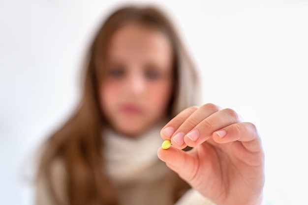 niña irreconocible sosteniendo una pastilla en la mano