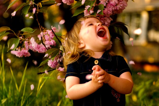 Niña en el jardín, bajo el árbol de sakura. Primavera