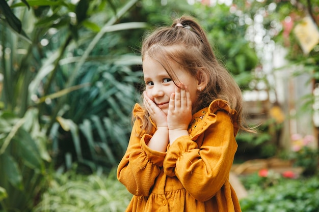 Niña en el jardín botánico Retrato de primer plano de un niño con el concepto de belleza de la salud del cabello oscuro