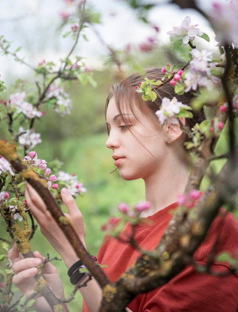 Una niña en un jardín floreciente mira árboles en flor