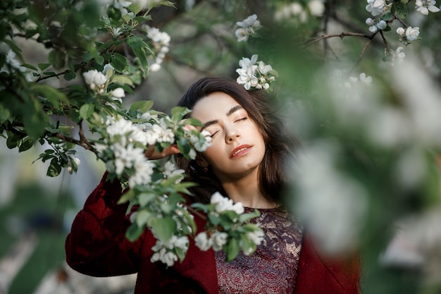 Niña en un jardín florido con un abrigo marrón