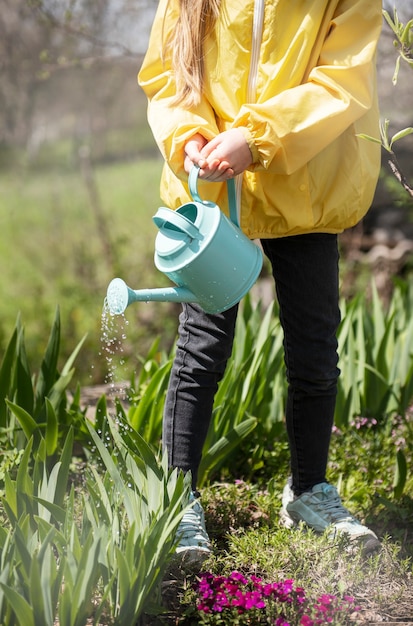 Niña en un jardín con regadera verde