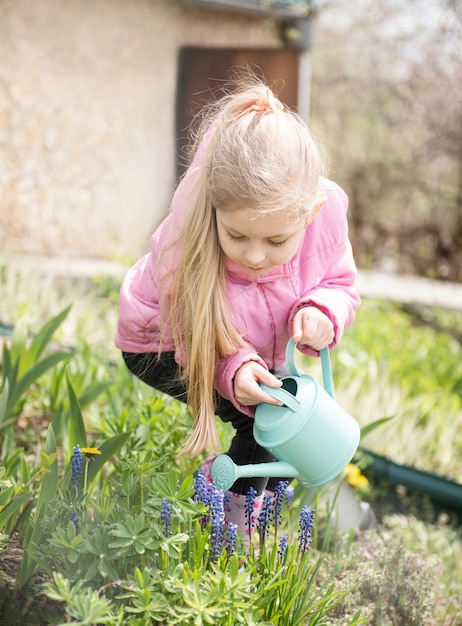 Niña en un jardín con regadera verde