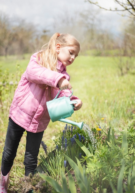 Niña en un jardín con regadera verde