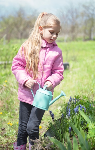 Niña en un jardín con regadera verde