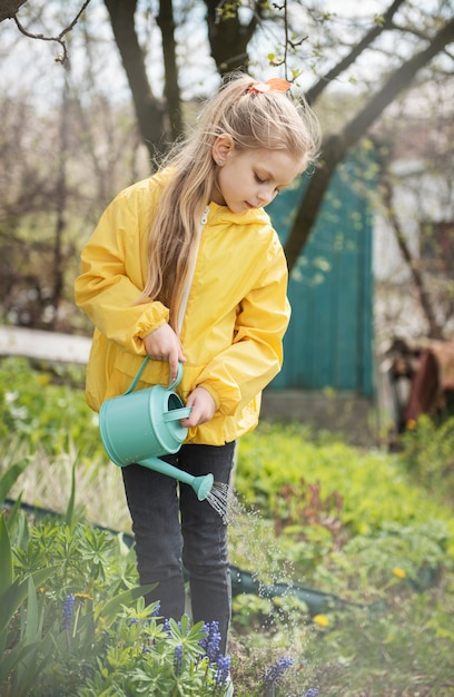 Niña en un jardín con regadera verde