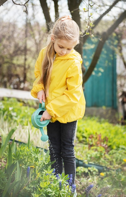 Niña en un jardín con regadera verde