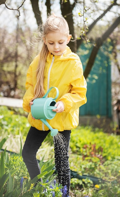 Niña en un jardín con regadera verde