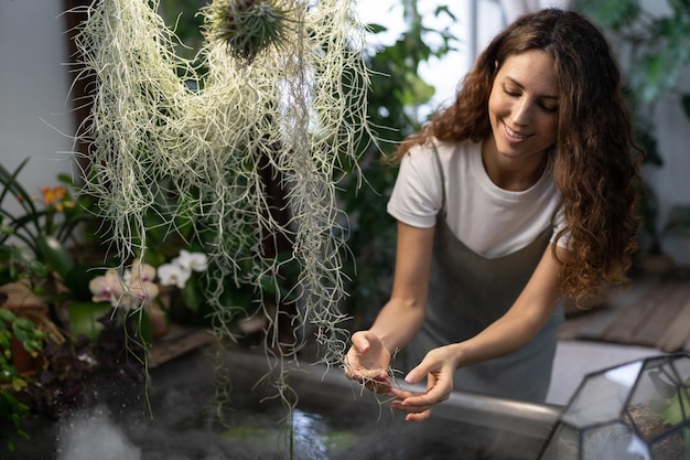 Niña jardinera cuidando plantas acuáticas en invernadero sosteniendo plantas de interior bajo el baño con agua