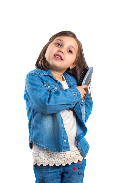 Niña en jeans con un peine en la mano, posando para la cámara