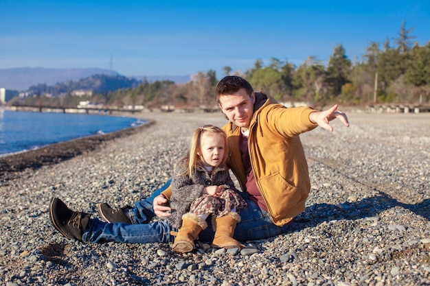 Niña y joven padre en la playa en un día soleado de invierno