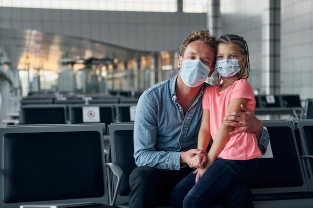 Con niña joven en ropa formal está en aeropuerto moderno