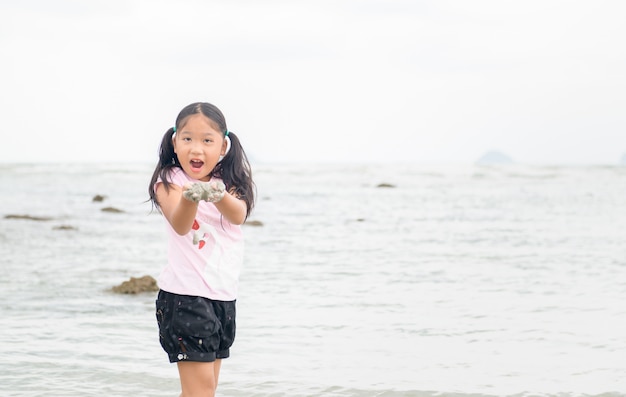 Niña juega arena en la playa