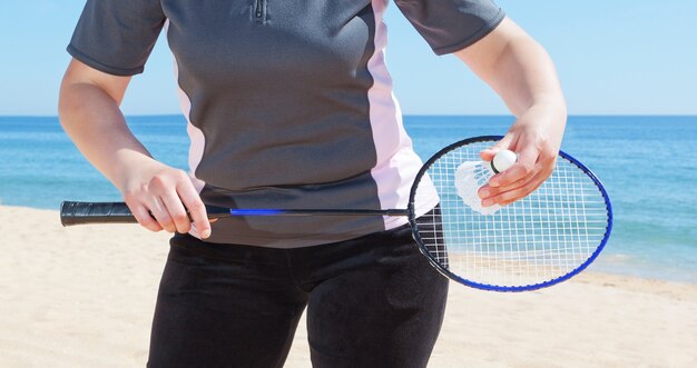 Una niña juega bádminton en la playa. De cerca.