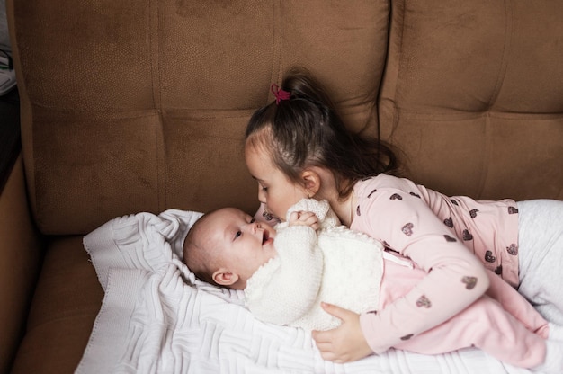 Una niña juega en la cama con su hermana recién nacida.