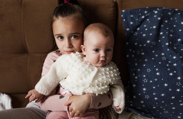 Una niña juega en la cama con su hermana recién nacida.