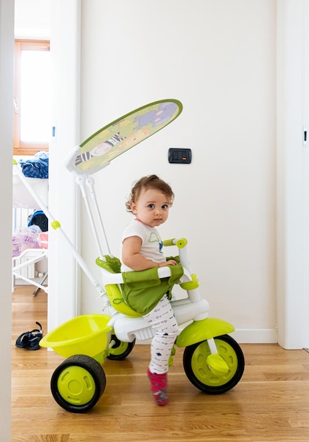 Niña juega en casa con triciclo