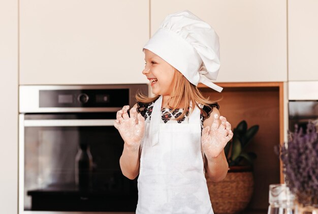 Niña juega en la cocina con harina y se ríe divertido