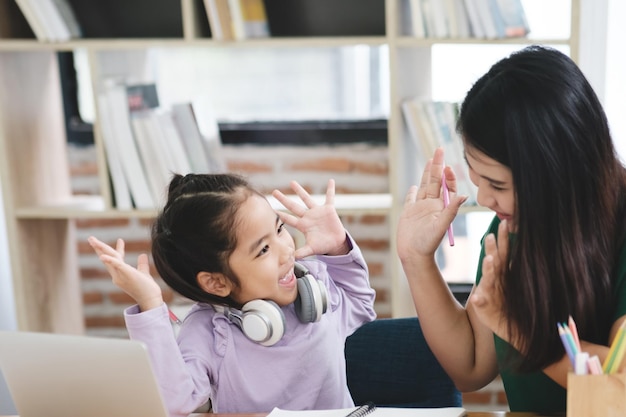 Una niña juega con una computadora portátil mientras su madre mira