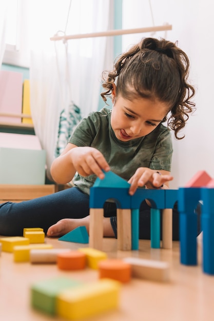 Foto niña juega concentrada con bloques de construcción