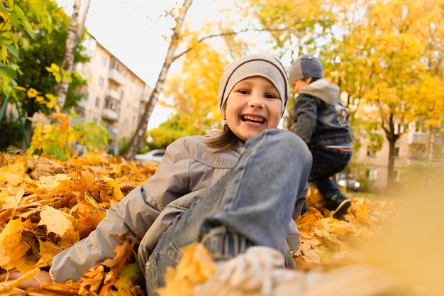 La niña juega en el follaje de otoño.