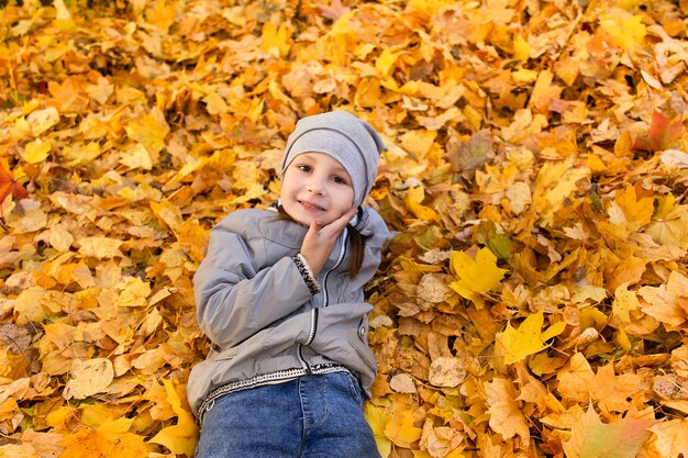 La niña juega en el follaje de otoño.