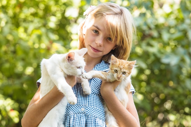 Niña juega con gatito al aire libre en el parque