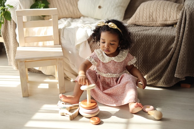 una niña juega con una pirámide de madera