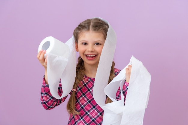 Una niña juega con un rollo de papel higiénico blanco.