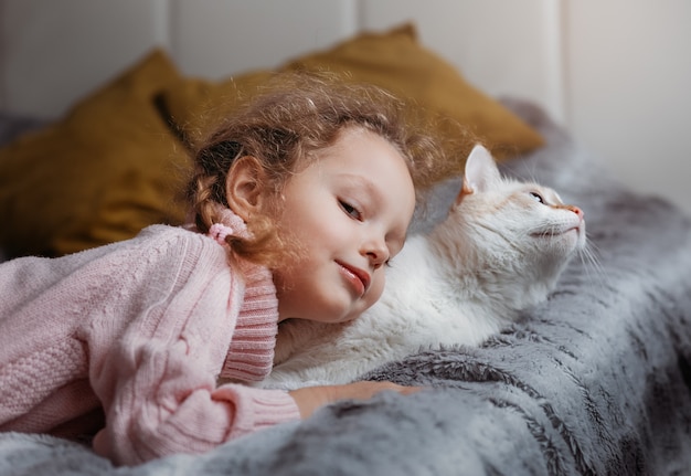 Niña juega en el sofá con su gato