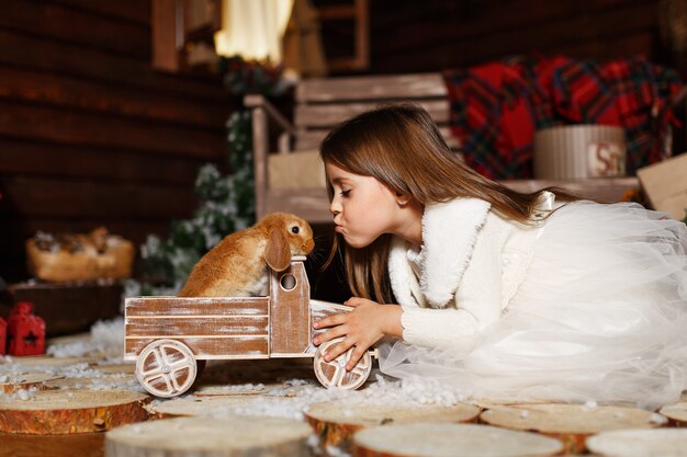 Una niña juega con su conejito en una fabulosa noche de Navidad.