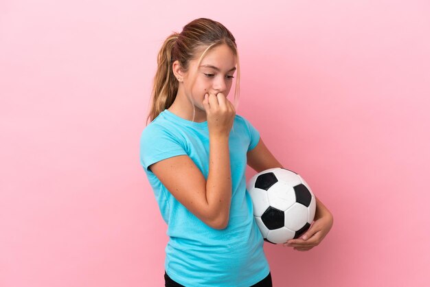 Niña jugadora de fútbol aislada de fondo rosa que tiene dudas