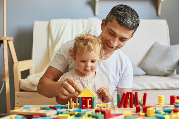 Niña jugando al clasificador con su padre en el salón pasando tiempo juntos después de una siesta papá cariñoso papá jugando con su hija usando juguetes educativos