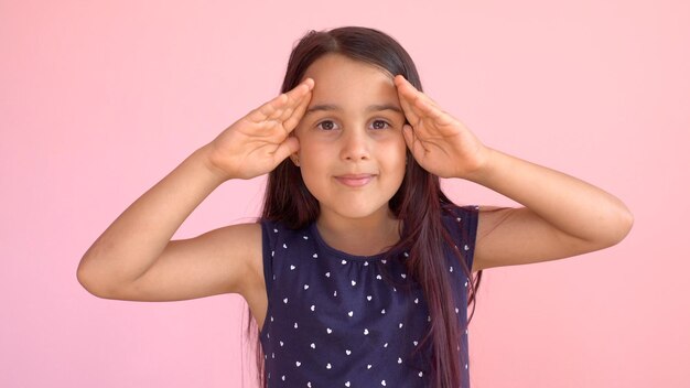 Niña jugando al escondite retrato. una niña linda abre la cara con las manos. jugando a las escondidas