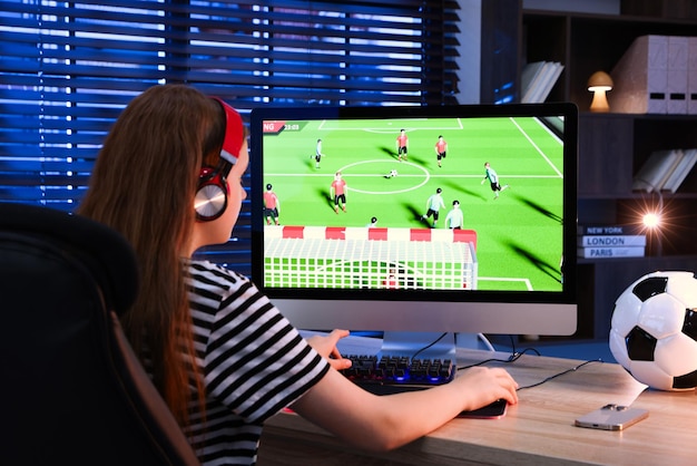 Niña jugando al videojuego con el teclado en la mesa en el interior de la vista trasera