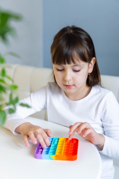 Niña jugando con arco iris pop it fidget El concepto de juguete popit de salud mental