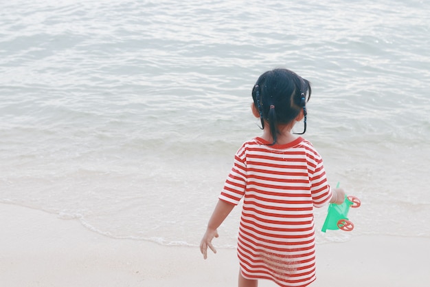 Niña jugando arena en la playa. Filtro retro