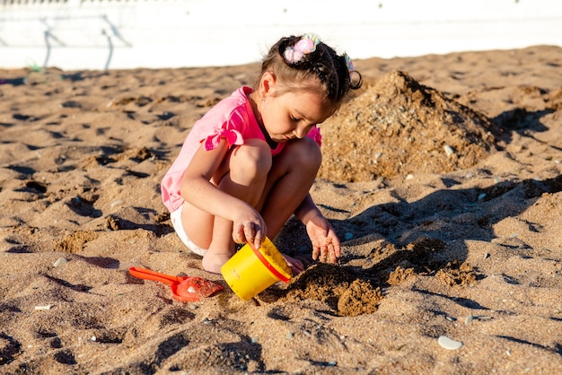 niña jugando con arena en la playa