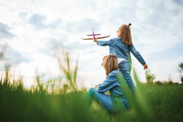 Niña jugando con avión cerca de madre