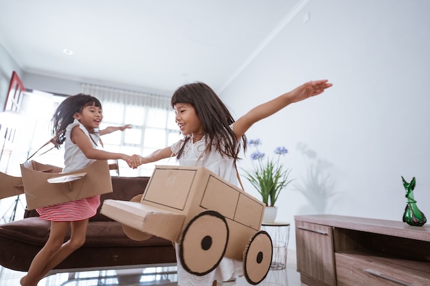 Niña jugando con avión de juguete de cartón en casa