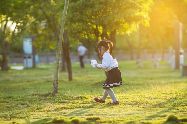 Una niña jugando con un avión de papel en el parque.