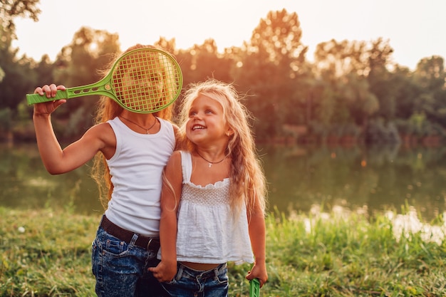 Niña jugando bádminton con su hermana en el parque de verano