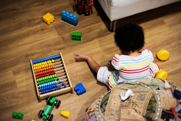 Niña jugando con bloques de construcción en el piso