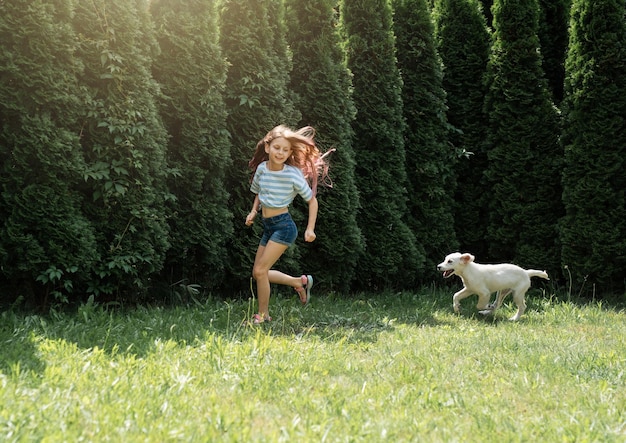 Niña jugando con un cachorro de golden retriever en el jardín Amigos en casa