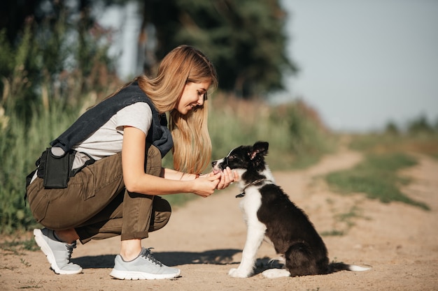 Niña jugando con cachorro de perro border collie blanco y negro en el camino del bosque