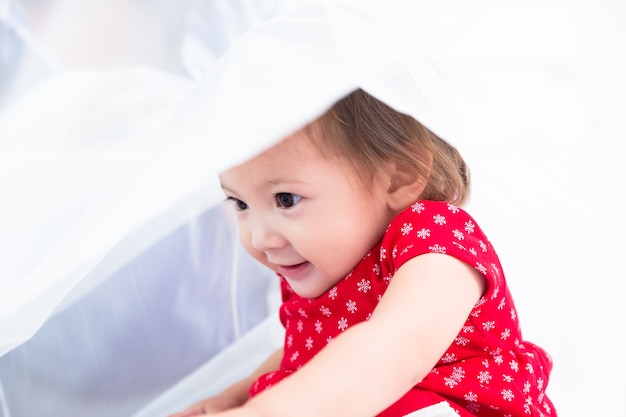 Niña jugando en la cama blanca