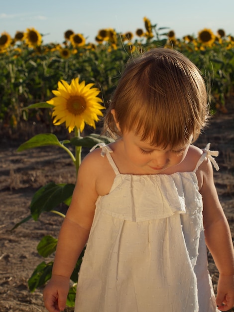 Foto niña jugando en el campo de girasol.