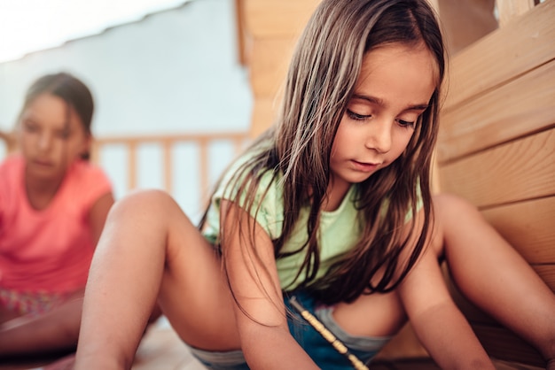 Niña jugando en la casa del árbol con amigos y dibujando con lápices de colores