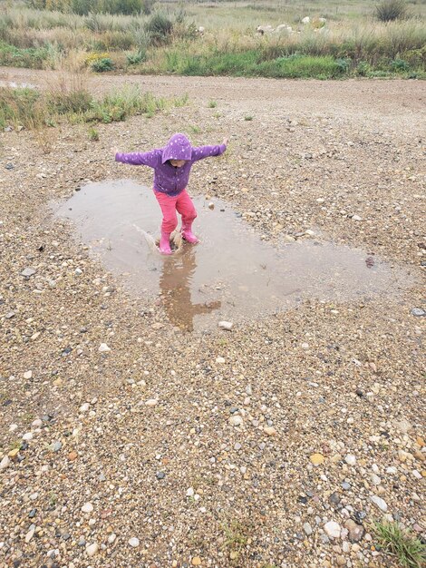 Foto niña jugando en un charco