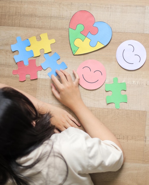 Niña jugando con un colorido rompecabezas de autismo Día Mundial de la Concienciación sobre el Autismo